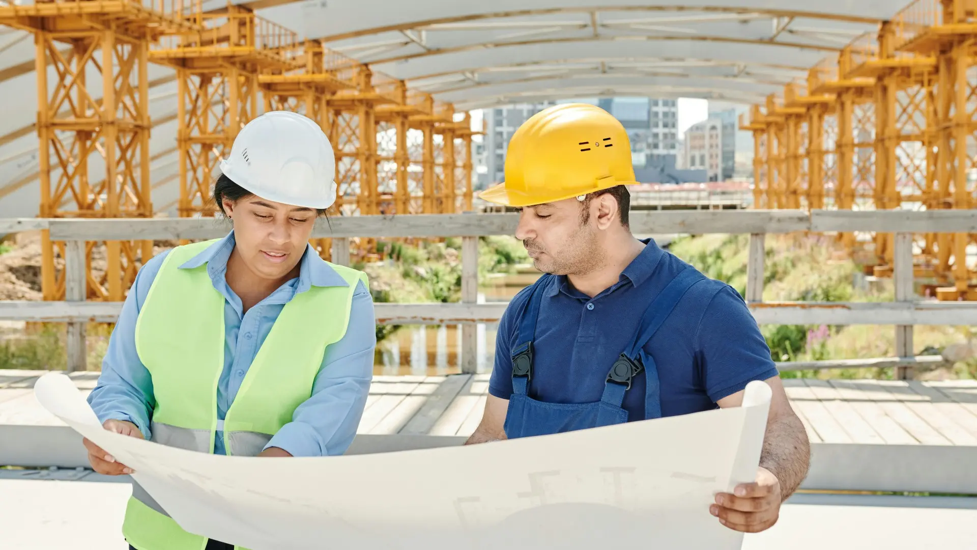 Two construction workers reviewing blueprints on a building site